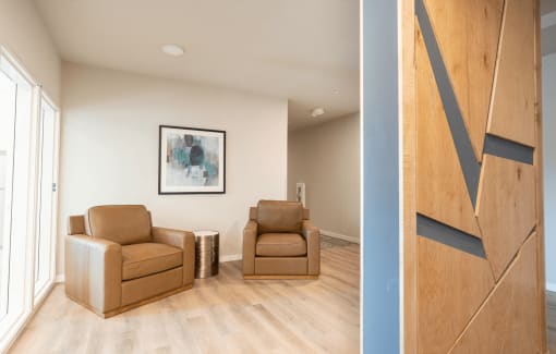 a living room with two brown chairs and a hallway with a blue accent wall