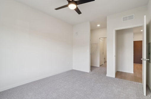 A room with a ceiling fan and carpeted floor.