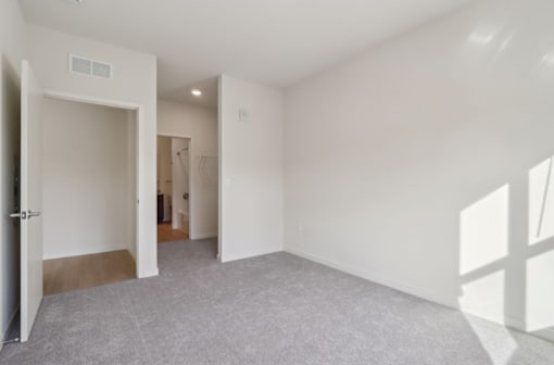 A room with white walls and a grey carpet.