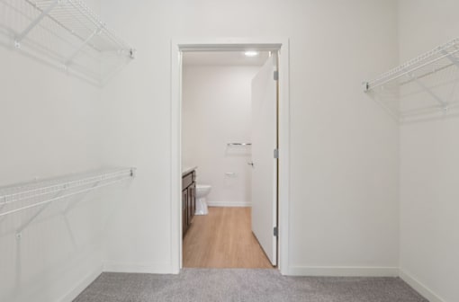 A white hallway with a doorway leading to a bathroom.