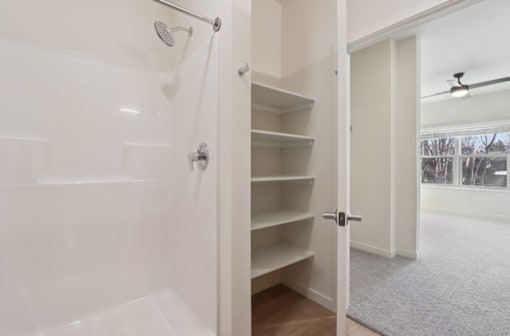 A white bathroom with a walk in shower and a white door.