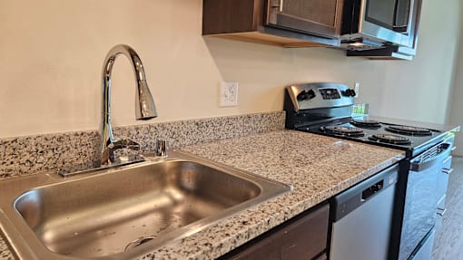 A kitchen with a granite countertop and stainless steel appliances.