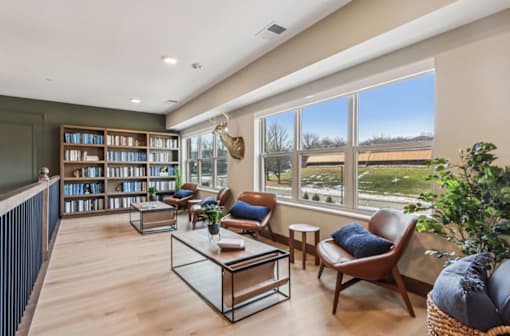 A living room with a large window, a bookshelf, and a leather chair.