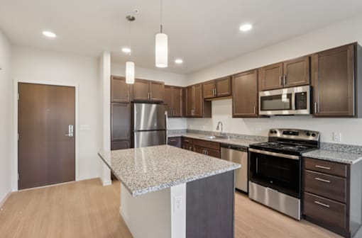 A kitchen with a granite countertop and stainless steel appliances.