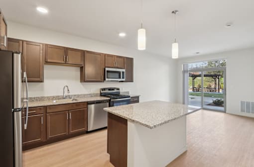 A kitchen with a refrigerator, microwave, oven, and sink.