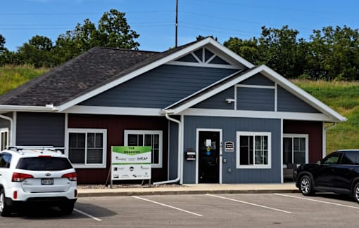 A small building with a red and blue exterior is surrounded by a parking lot.