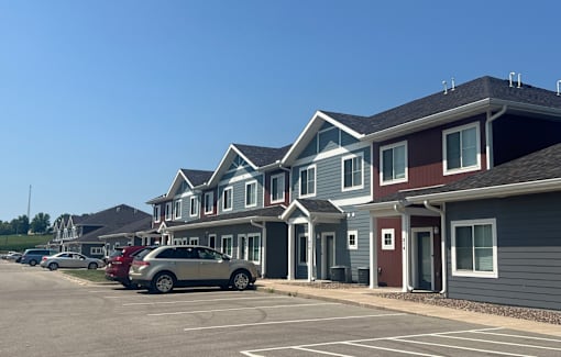 A row of houses with cars parked in front.