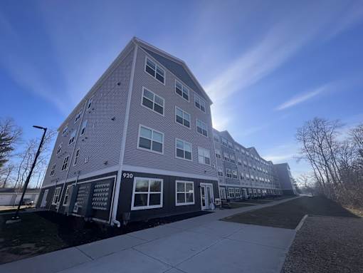 a three story apartment building with a sidewalk in front of it