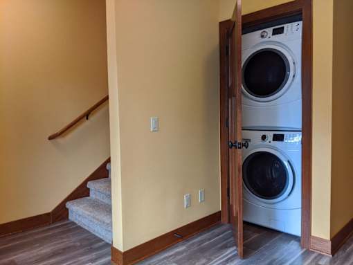 A washer and dryer are in a small wooden cabinet in a home.