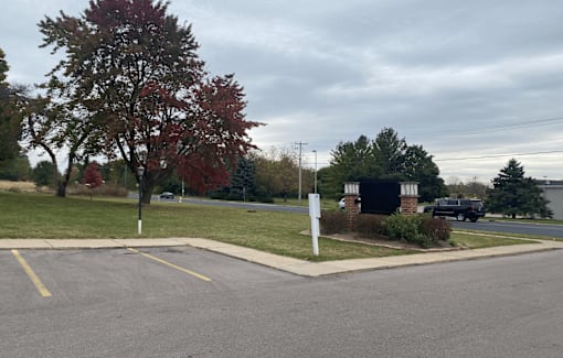 A parking lot with a sign and a tree with red leaves.