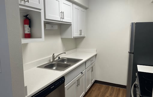 A kitchen with white cabinets and a black dishwasher.