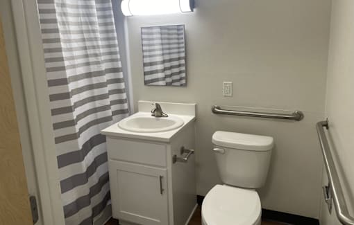 A bathroom with a toilet, sink, and striped shower curtain.