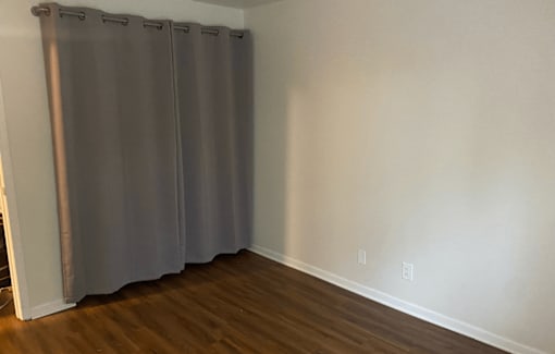 A room with a grey curtain and wooden floor.