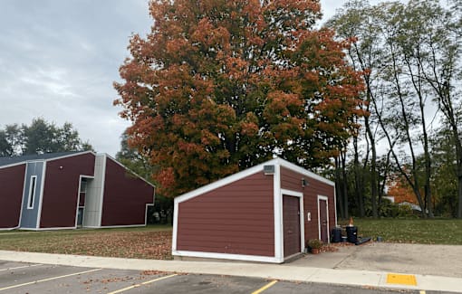A red building with a white door is situated in a parking lot.