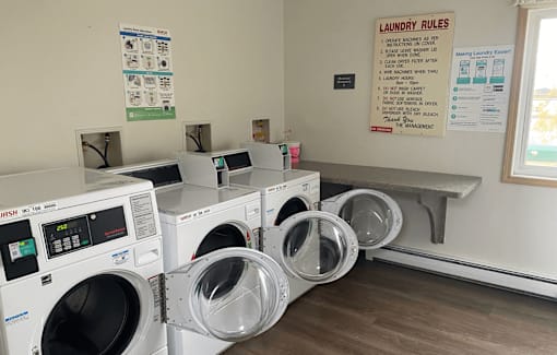 A laundry room with washing machines and a laundry rules sign.