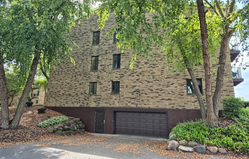 A house with a black garage door is surrounded by trees.