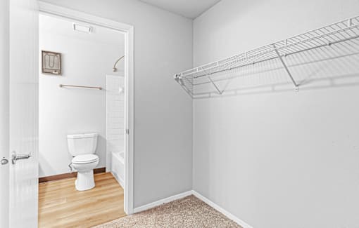 A white bathroom with a toilet and a shelf.
