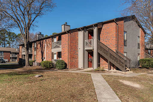 A brick building with a red door and a balcony.