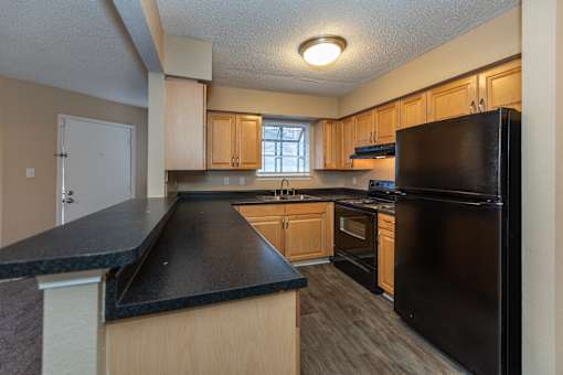 A kitchen with black countertops and wooden cabinets.