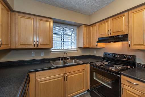 A kitchen with wooden cabinets and black countertops.