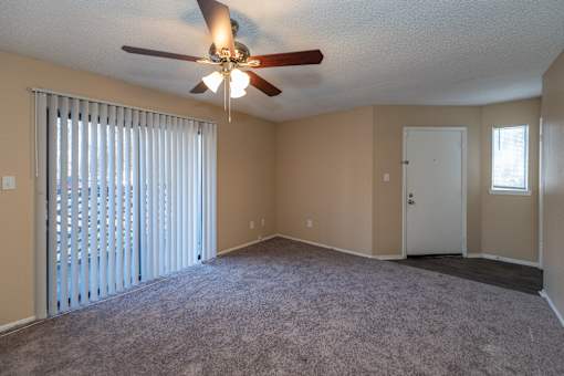 A room with a ceiling fan and carpeted floor.