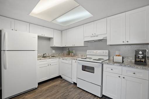 A white kitchen with a refrigerator, oven, and cabinets.