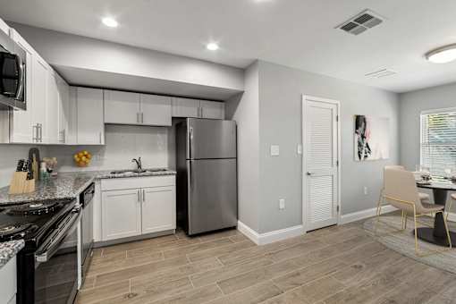A kitchen with a refrigerator, stove, and cabinets.