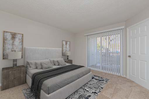 A bedroom with a large bed and a window with blinds.