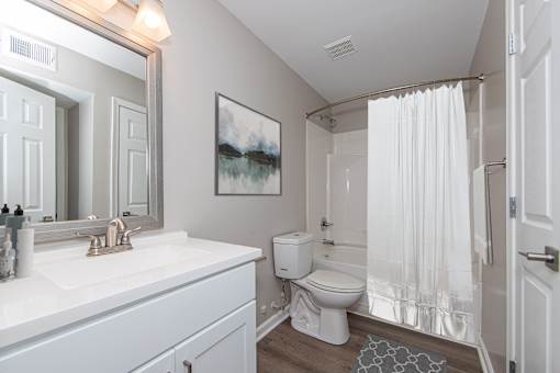 A white bathroom with a toilet, sink, and shower.