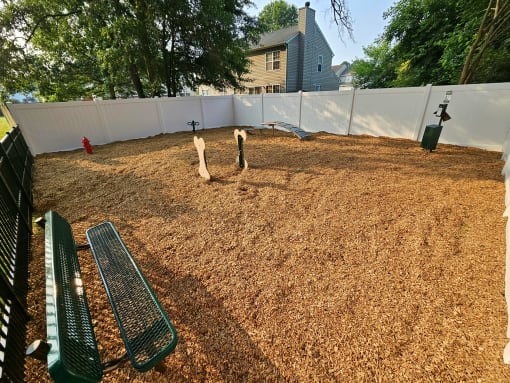 a view of the dog park with a bench in the foreground and a house in the background