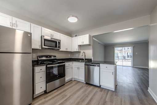 A kitchen with stainless steel appliances and white cabinets.