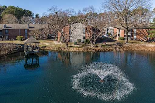 A fountain in the middle of a lake in a residential area.