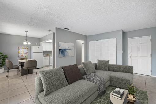 A living room with a grey couch and a dining table.