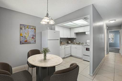 A kitchen with a table and chairs in the foreground and a refrigerator in the background.