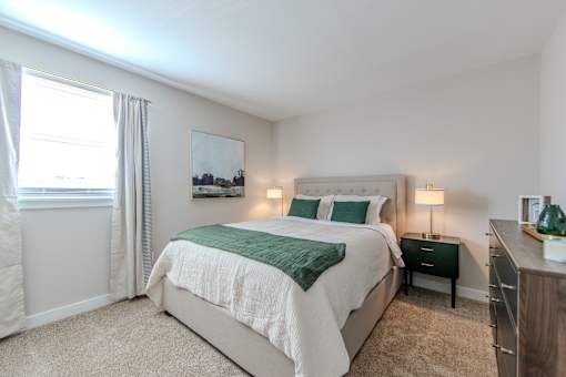 A bedroom with a large bed and a painting on the wall.