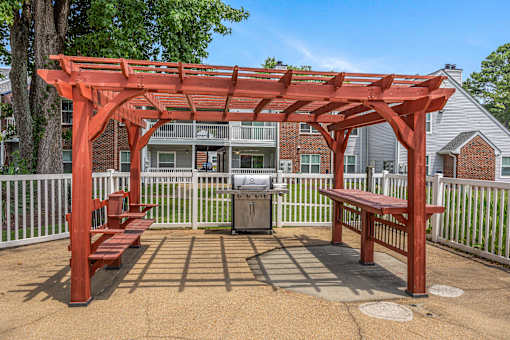 A red pergola with benches is in the foreground of a residential area.