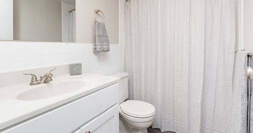 A white bathroom with a toilet, sink, and shower curtain.