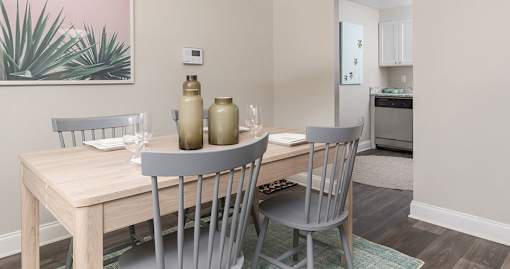A dining table with two chairs and a potted plant on the side.