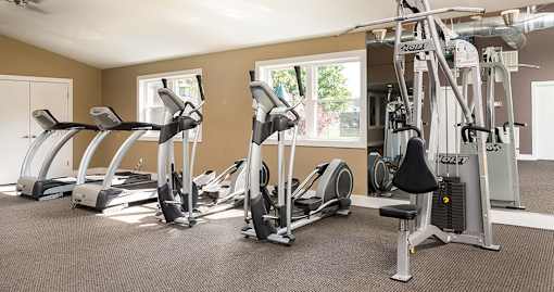 A fitness center with a weight machine, treadmills and ellipticals