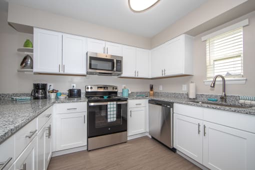 newly renovated kitchen with white cabinets, stainless steel appliances, and granite countertops