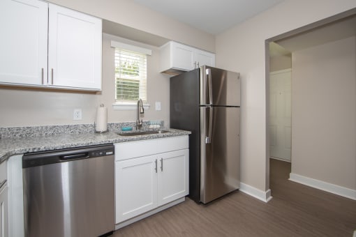 newly renovated kitchen with white cabinets, stainless steel appliances, and granite countertops