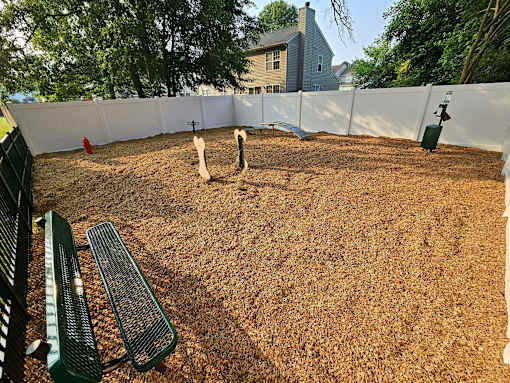 A backyard with a white fence and a green bench.