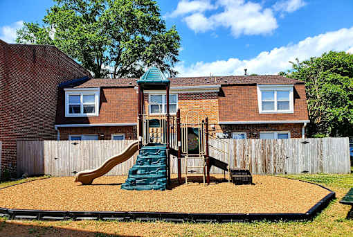 A backyard with a playground and a house.