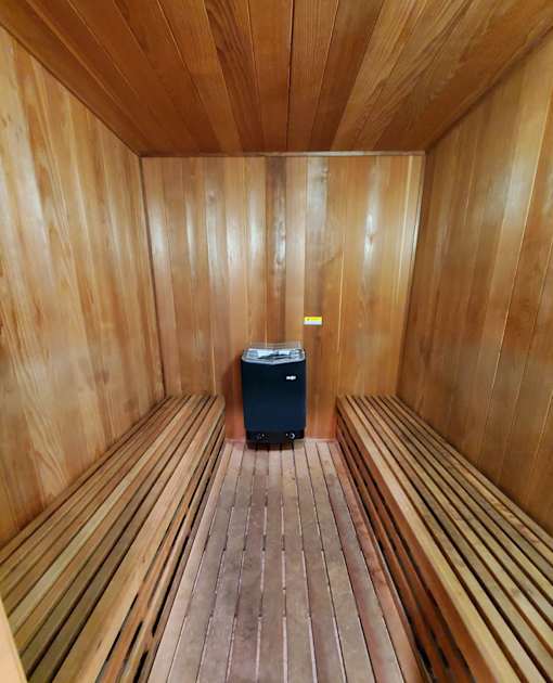 A wood sauna with benches and a heater.