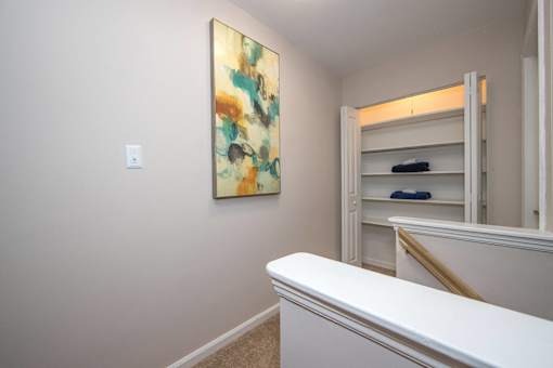 A painting hangs on a wall above a white counter in a room.