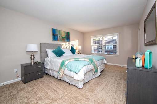A bedroom with a large bed and a painting on the wall.
