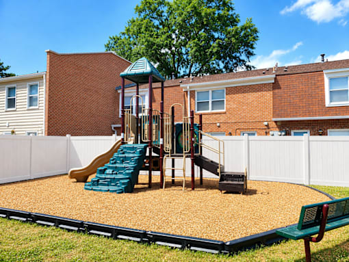 A playground with a green slide and a green bench.