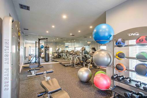 A gym with a variety of equipment including weights and exercise balls.