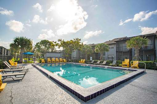 A sunny day at the pool with yellow lounge chairs.