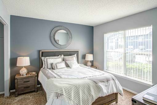A bedroom with a large bed, two nightstands, and a round mirror on the wall.